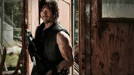 Daryl Dixon, portrayed by Norman Reedus, stands confidently with a crossbow in this HD wallpaper from The Walking Dead, set against a weathered backdrop.