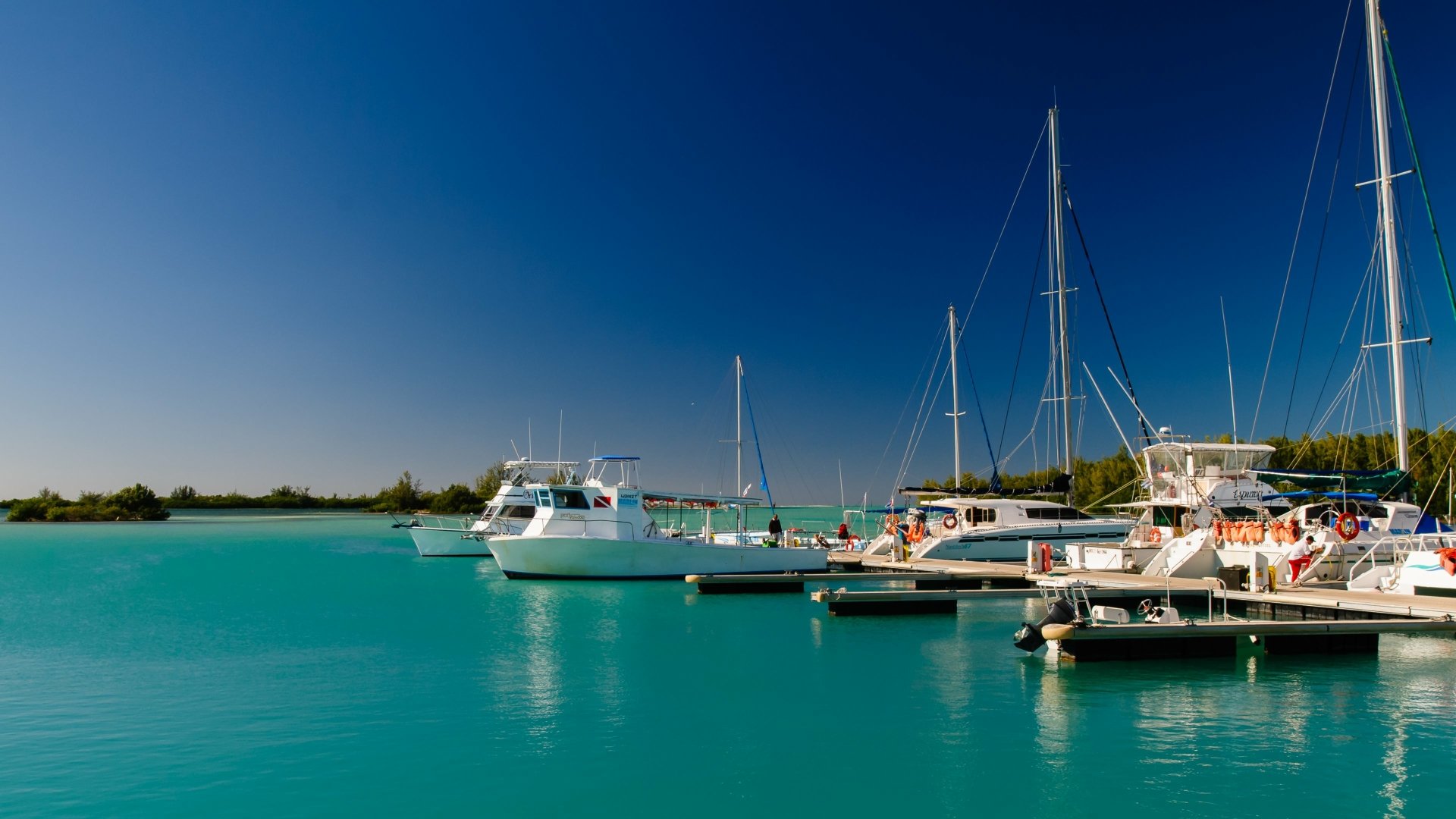4K Ultra HD PC desktop wallpaper/background of boats (vehicle) moored in a sunlit marina over turquoise water beneath a clear blue sky.
