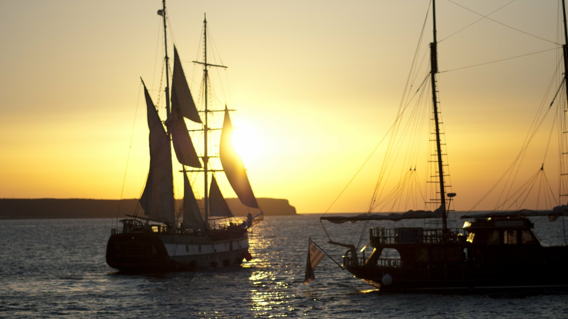 4K Ultra HD PC desktop wallpaper showing two sailing ships (vehicle, ship) silhouetted on calm water at golden sunset.