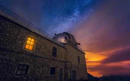 HD PC desktop wallpaper featuring a sci-fi scene with a stone observatory building under a vibrant Milky Way galaxy and glowing sunset sky.
