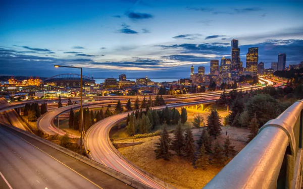 4K Ultra HD time-lapse view of Seattle’s city skyline with illuminated roads winding through the urban landscape under a twilight sky.