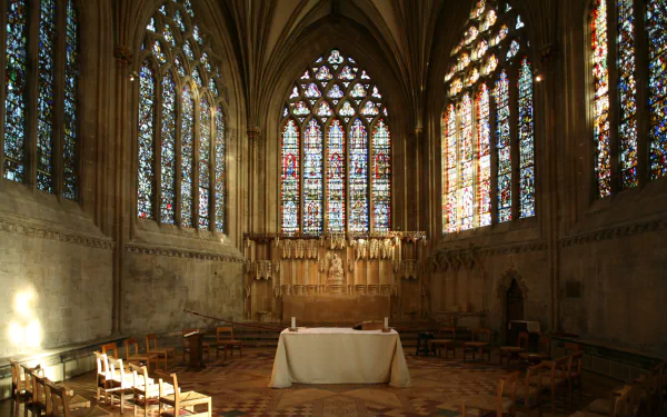 Interior of Wells Cathedral showcasing intricate stained glass windows and a central altar, captured in an HD desktop wallpaper highlighting its religious architecture.