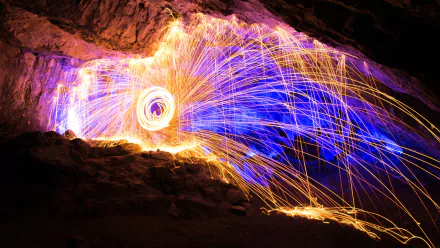 4K Ultra HD night photography of vibrant fireworks lighting a rocky cave interior with dynamic sparks and glowing trails, creating a dramatic and colorful display.