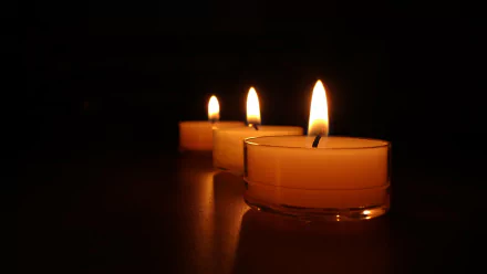 HD desktop wallpaper featuring three lit candles in a dark setting, creating a serene and warm ambiance.