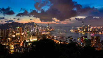 A stunning 4K Ultra HD view of Hong Kong’s skyline at dusk, showcasing towering skyscrapers, the vibrant harbor, and a dramatic cloud-filled sky.