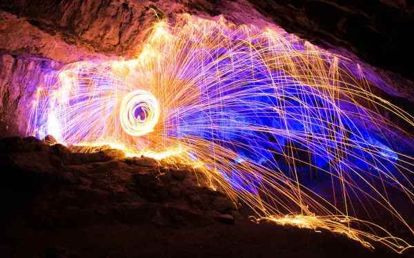 4K Ultra HD night photography of vibrant fireworks lighting a rocky cave interior with dynamic sparks and glowing trails, creating a dramatic and colorful display.