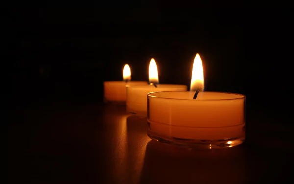 HD desktop wallpaper featuring three lit candles in a dark setting, creating a serene and warm ambiance.