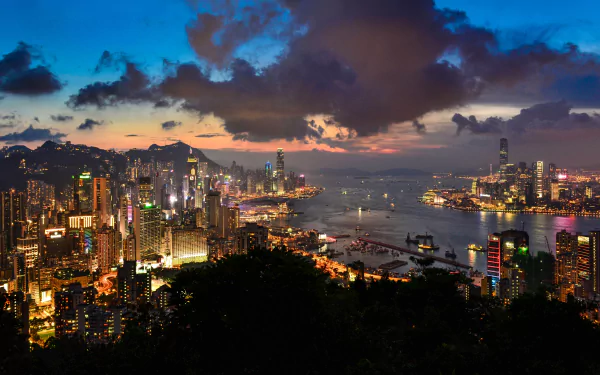 A stunning 4K Ultra HD view of Hong Kong’s skyline at dusk, showcasing towering skyscrapers, the vibrant harbor, and a dramatic cloud-filled sky.