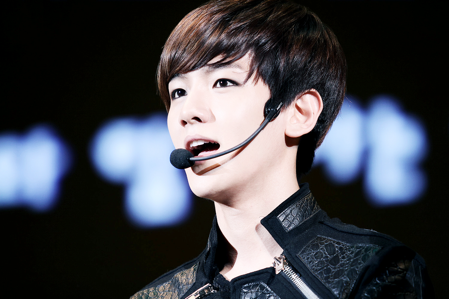 HD PC desktop wallpaper featuring a close-up of an EXO member wearing a microphone headset during a music performance.
