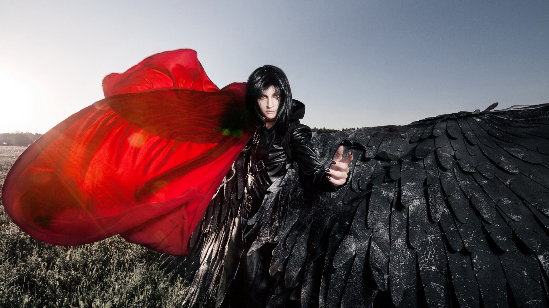 A woman in striking cosplay, featuring dramatic wings and a flowing red cape, stands confidently against a scenic backdrop, creating an eye-catching HD desktop wallpaper.