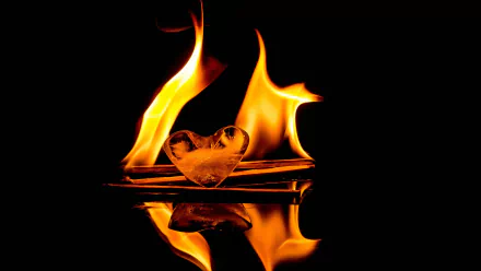 A stunning 4K Ultra HD image featuring flames dancing around a heart-shaped ice sculpture, reflecting beautifully against a dark background.