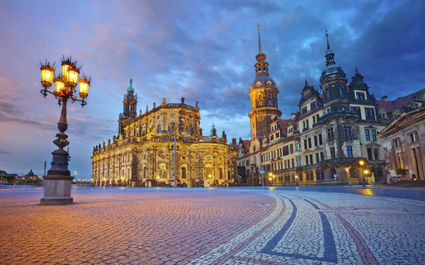 A stunning HD view of Dresden, Germany, showcasing beautiful man-made architecture illuminated at dusk, with cobblestone streets and dramatic clouds overhead.