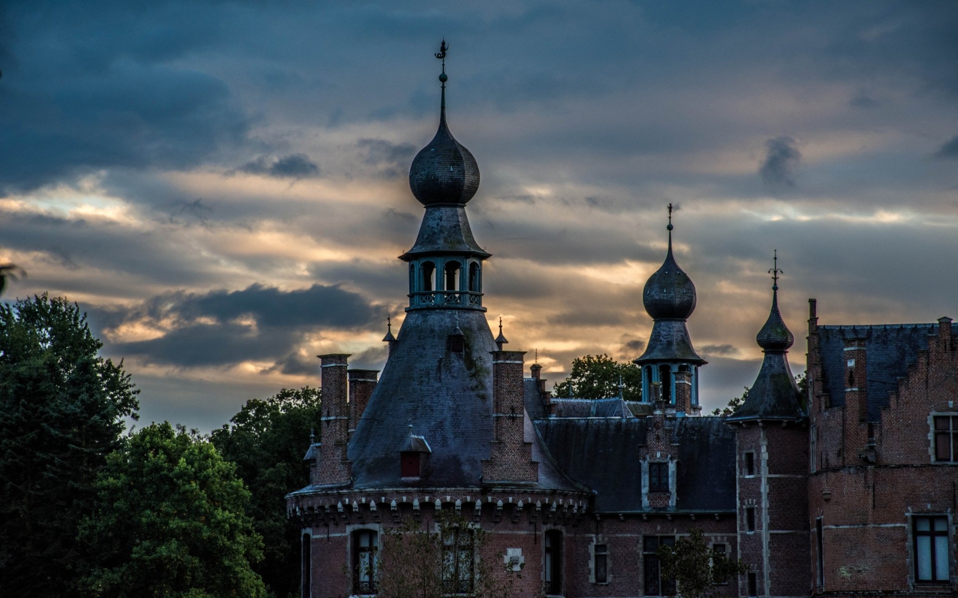 2K Quad HD PC desktop wallpaper of Ooidonk Castle, a man-made historic castle with onion-shaped spires and turrets silhouetted against a dramatic twilight sky.