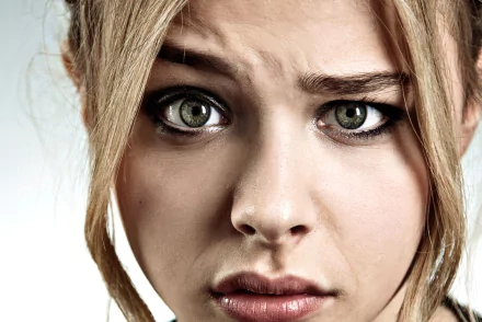 A close-up of Chloë Grace Moretz, capturing an intense expression with her striking green eyes. This HD wallpaper offers a dramatic background for desktop use.