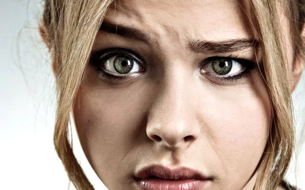A close-up of Chloë Grace Moretz, capturing an intense expression with her striking green eyes. This HD wallpaper offers a dramatic background for desktop use.