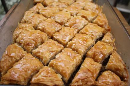 Close-up of golden glazed baklava squares with glossy honey and flaky layers in a pan — food wallpaper in 4K Ultra HD PC desktop background.