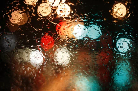 A captivating HD photo of raindrops on a window, blurring vibrant city lights in the background, creating a serene, atmospheric wallpaper for your desktop.