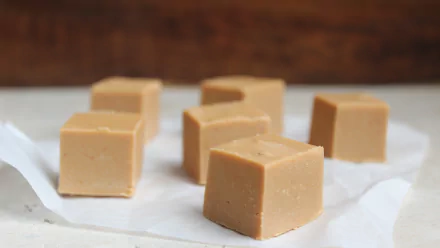 Close-up of smooth peanut butter fudge cubes on parchment paper, captured in 4K Ultra HD for a rich and detailed food desktop wallpaper.
