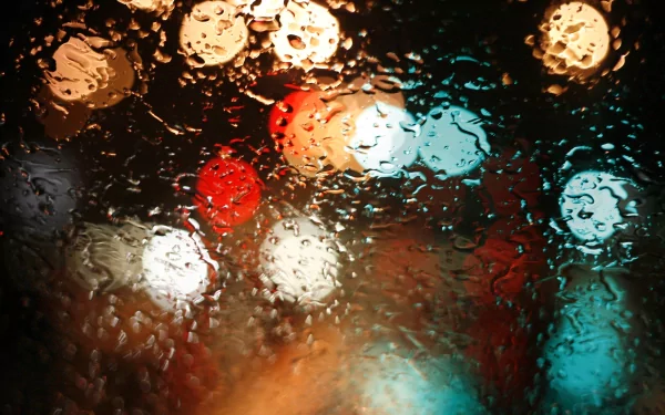 A captivating HD photo of raindrops on a window, blurring vibrant city lights in the background, creating a serene, atmospheric wallpaper for your desktop.