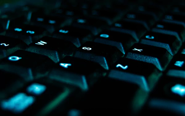 A close-up view of a dark keyboard with illuminated blue keys, showcasing a modern technology theme in a 4K Ultra HD desktop wallpaper format.