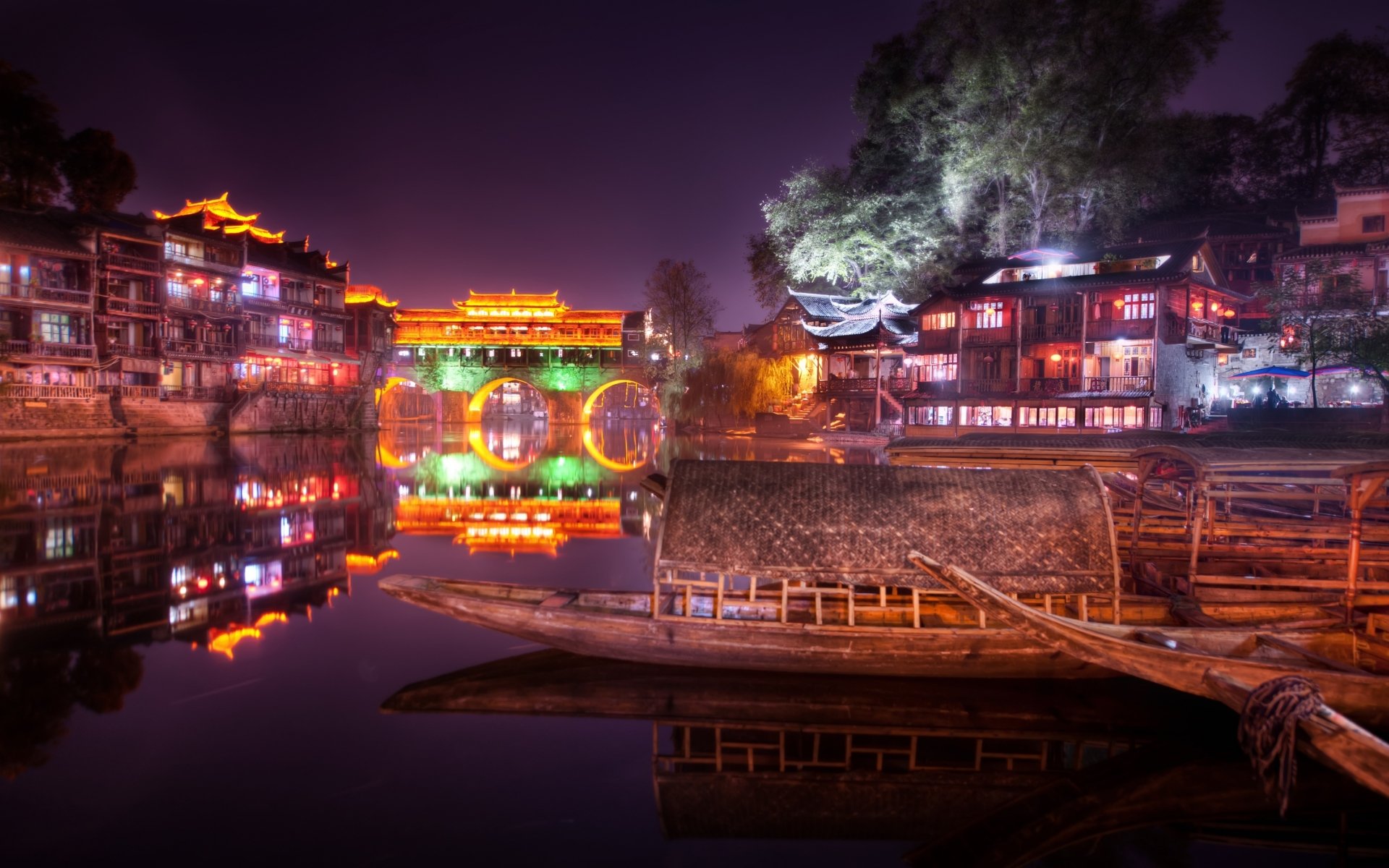 Night view of a man-made town in China, illuminated buildings reflecting on calm water, captured in stunning 4K Ultra HD quality.