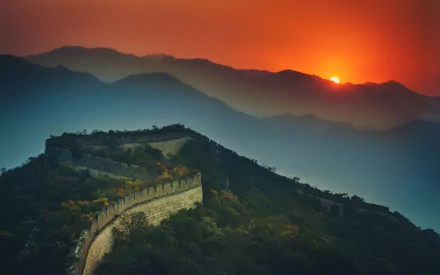 A stunning sunset over the Great Wall of China, showcasing the man-made structure against a backdrop of mountainous terrain and vibrant colors. 4K Ultra HD wallpaper.