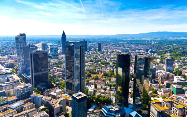 A stunning cityscape of Frankfurt, Germany, showcasing its modern skyscrapers and lush greenery under a clear blue sky, captured in vibrant 4K Ultra HD.