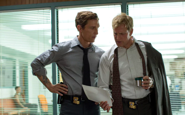 HD desktop wallpaper of two detectives in shirts and ties with badges, one reading a file, the other holding coffee in a glass-walled office — TV crime-drama scene.