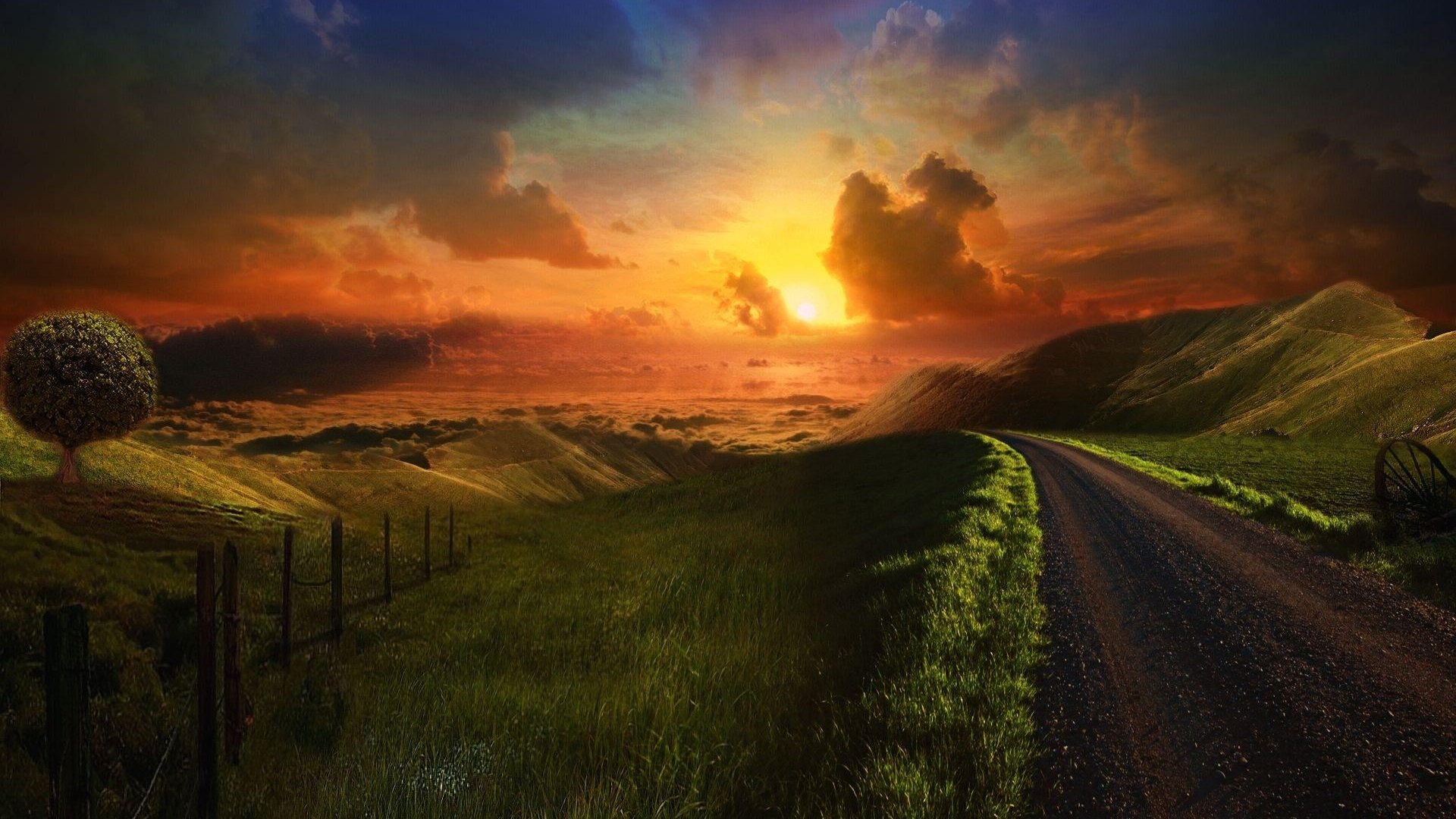 HD desktop wallpaper featuring a scenic sunset over rolling hills and a winding road, accentuated by vibrant sky colors and lush greenery.