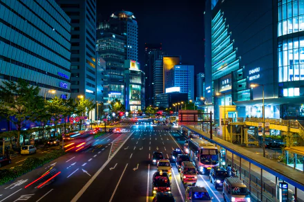 A vibrant night street scene in Osaka, Japan, showcasing bustling traffic and illuminated skyscrapers, captured in HD. The dynamic lights and urban landscape make for a striking desktop wallpaper and background.