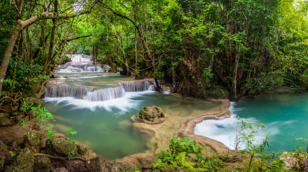 HD desktop wallpaper showcasing a serene stream flowing through lush greenery in Thailand’s vibrant natural landscape.