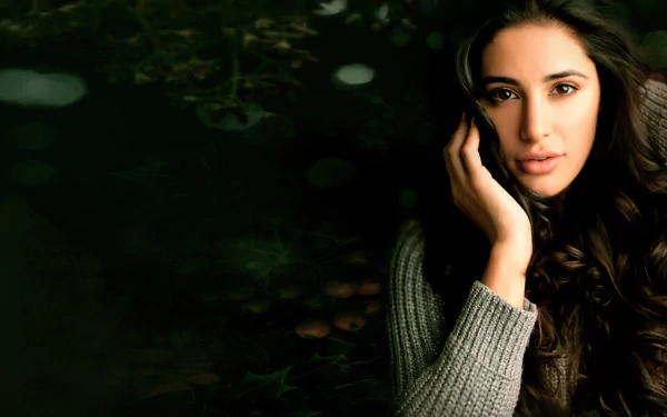 HD desktop wallpaper featuring brunette celebrity and model Nargis Fakhri against a dark, blurred natural background.