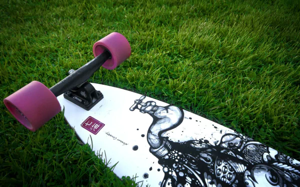 HD desktop wallpaper of a skateboard with pink wheels resting on green grass, showcasing dynamic sports-themed artwork on the deck.