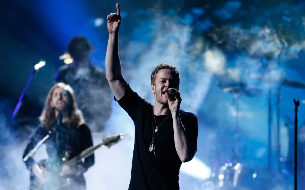 An American alternative band, Imagine Dragons, performing passionately on stage. The image captures the energy of live music with dramatic lighting and a smoky background.