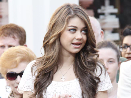 HD desktop wallpaper featuring a woman with wavy hair and a white top, amidst a crowd.