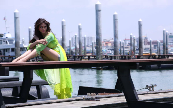 Aditi Rao Hydari featured in a Bollywood-themed, HD desktop wallpaper. She poses on a dock in a vibrant green outfit, with a background of boats and cityscape under a clear sky.