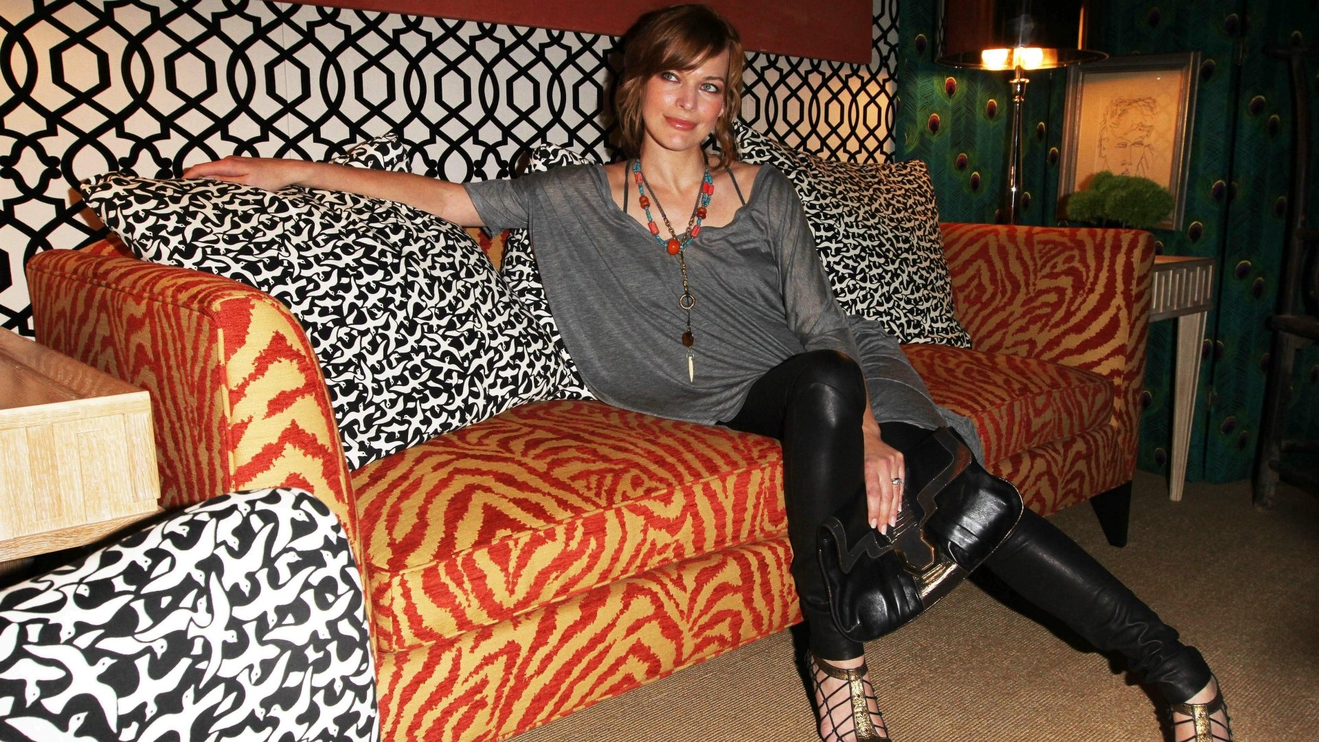 Portrait of a celebrity seated on a bold patterned sofa in an eclectic room — 4K Ultra HD PC desktop wallpaper/background.