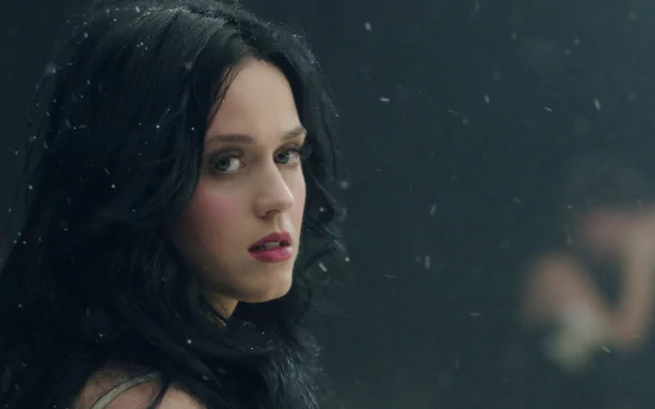 A striking HD desktop wallpaper featuring Katy Perry, capturing her enigmatic expression amidst a backdrop with soft falling particles, embodying the essence of music and artistry.