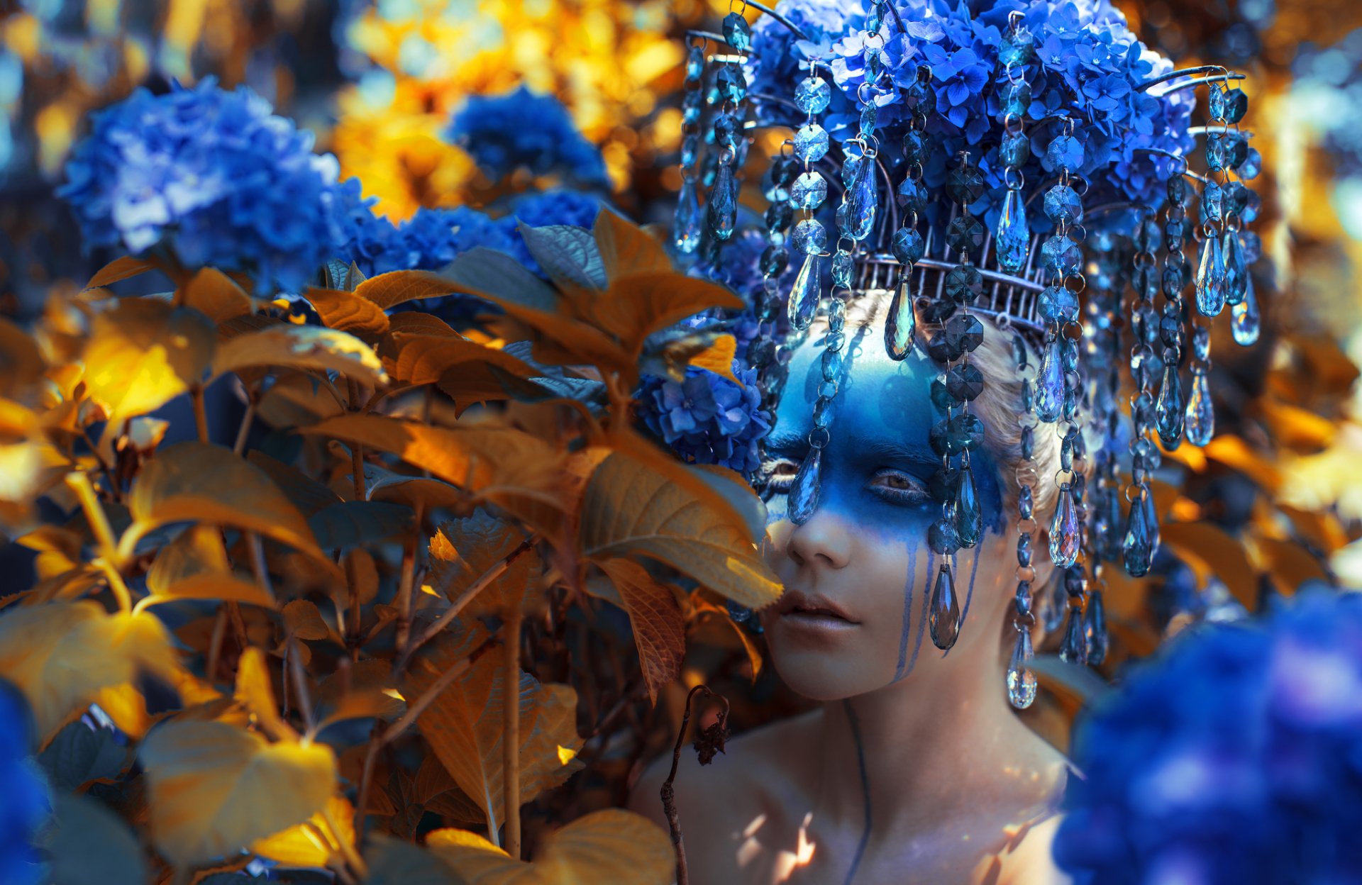 An artistic HD PC desktop wallpaper featuring a woman with elaborate blue headpiece blending into vibrant blue and orange floral surroundings.