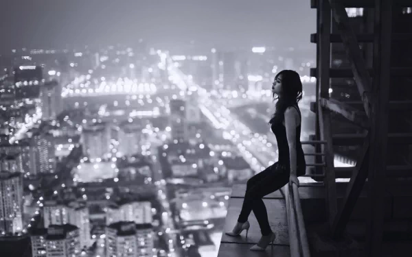 HD desktop wallpaper featuring an Asian woman sitting on a rooftop edge, overlooking a brightly lit cityscape at night.