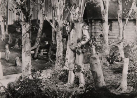 Black-and-white 2K Quad HD PC desktop wallpaper: Tin Man stands among birch trees in a forest, a still from the movie The Wizard of Oz (1939).