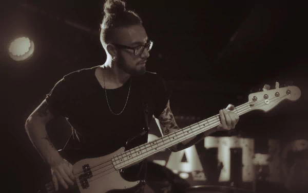 HD desktop wallpaper of Being As An Ocean's bass player performing live on stage, immersed in the music.