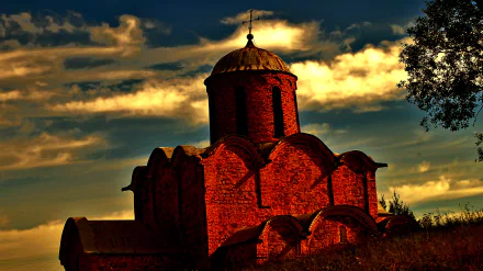 2K Quad HD PC desktop wallpaper — red-brick church with rounded dome silhouetted against dramatic golden clouds at sunset, religious church background.