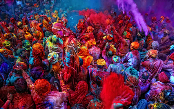 A vibrant scene of people celebrating Holi, with colorful powders filling the air, creating a lively and joyful atmosphere. An HD wallpaper capturing the essence of this festive holiday.
