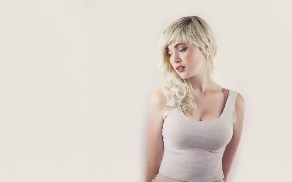 A high-definition desktop wallpaper featuring Devon Jade, a woman with blonde hair, thoughtfully gazing down, dressed in a light-colored top against a soft background.