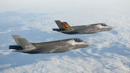 Two Lockheed Martin F-35 Lightning II military jets flying above the clouds in this HD PC desktop wallpaper and background.