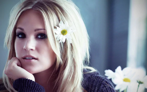 HD desktop wallpaper featuring a close-up of singer Carrie Underwood with a white daisy in her blonde hair, evoking a soft, natural music-inspired vibe.
