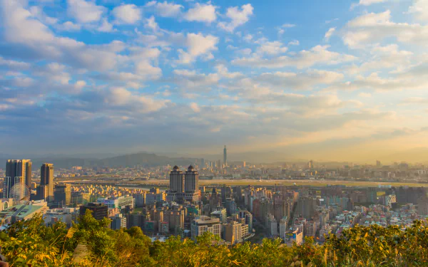 A vibrant 4K Ultra HD view of Taipei’s cityscape under a partly cloudy sky, showcasing man-made structures and the natural beauty of Taiwan.