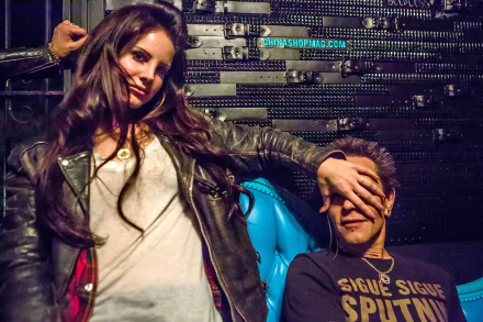 HD PC desktop wallpaper featuring musician Lana Del Rey playfully covering a man's face against a textured, dark background.