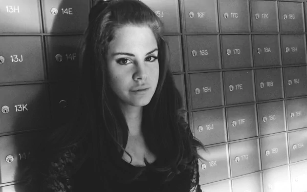 Black and white HD desktop wallpaper featuring Lana Del Rey standing against a wall of numbered lockers, capturing a moody and vintage music vibe.